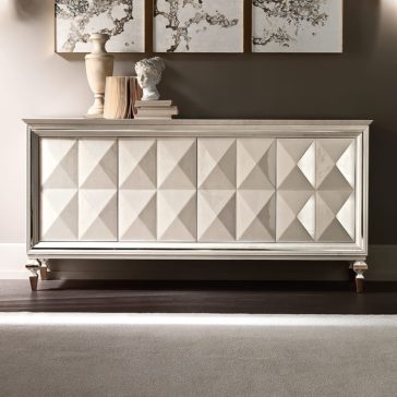 Italian Diamond Design Mother of Pearl Sideboard The Italian Diamond Design Mother of Pearl Sideboard features a stylish Italian diamond pattern on its doors, complemented by light wood finishes and decorative details. The top is adorned with books, a classical-style bust, and vases, while abstract framed artworks provide a captivating backdrop on the wall behind it.