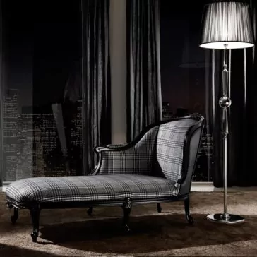 A modern black-and-white Classic Houndstooth Louis High End Designer Chaise Longue with plaid upholstery sits beside a tall floor lamp, in front of large windows overlooking the city skyline at night. Represents a Wednesday inspired interior design style.