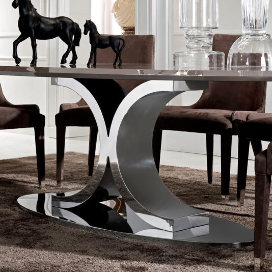 The Contemporary Italian Oval Dining Table features a reflective, curved metal base paired with a glossy, rectangular tabletop adorned with two dark horse figurines in different sizes. This elegant table is surrounded by brown upholstered chairs and complemented by decorative glass elements in the background.