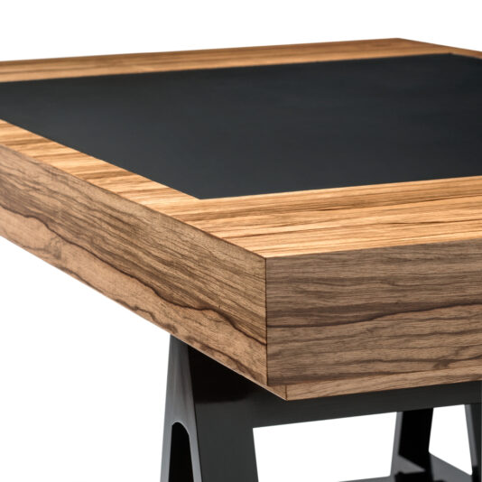 The High End British Designer Contemporary Trestle Desk features a sleek design with a thick wooden edge showcasing a natural, light brown grain, and a smooth black top surface. Its angled black legs provide a stylish contrast to the wood and black top, epitomizing contemporary elegance.