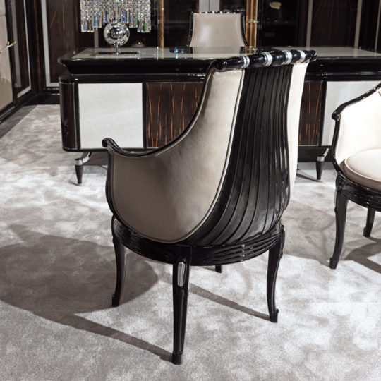 The Exclusive Designer Italian High Gloss Lacquered Leather Chair in black and beige with curved wood accents sits on a light gray carpet, paired with an elegant desk and matching furniture in a modern office.