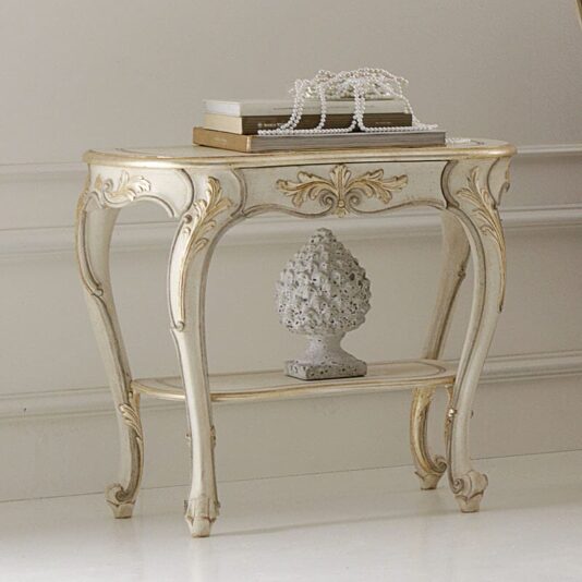 Opulent Carved Italian Bedside Table An Opulent Carved Italian Bedside Table with gold detailing, adorned with a stack of books and a string of pearls. Below, there is a decorative finial statue on the lower shelf. The table stands against a white wall with crown molding in a classic interior setting.