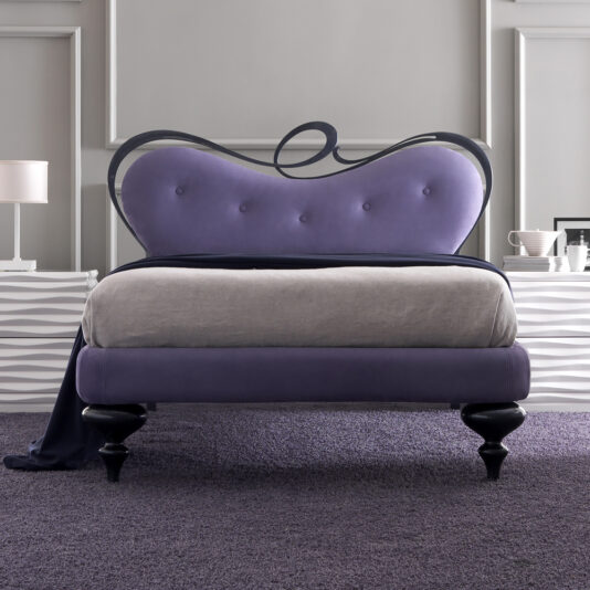 A stylish bedroom showcases the Romantic Nubuck Leather Upholstered Bed, featuring a curvy purple frame, gray bedding, dark wood legs, and a matching purple carpet, complemented by modern decor with white side tables and neutral walls.