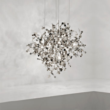 Silver Italian Designer Pendant Light The Silver Italian Designer Pendant Light, crafted from numerous reflective circular discs, features an abstract, clustered design. This chandelier casts intricate shadows and highlights on the surrounding minimalist white space with its soft edges and smooth surface.