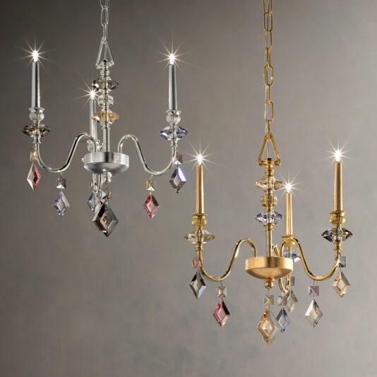 Small Candle Style Gold Plated Chandelier Two elegant chandeliers are displayed, one with a silver finish and the Small Candle Style Gold Plated Chandelier. Both feature hanging crystal ornaments that catch light, creating a sparkling effect. The background is a simple, muted gray, highlighting the chandeliers' intricate designs.