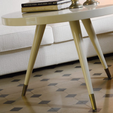 Contemporary Italian Designer Side Table A close-up of the Contemporary Italian Designer Side Table with its distinctive tapered legs and elegant brass caps, situated on a patterned floor. The table's sleek white surface is adorned with two books and a metallic lamp, while part of a white upholstered sofa can be seen in the background.