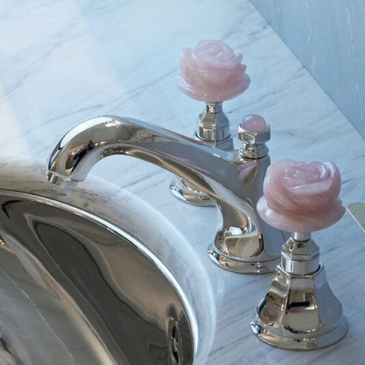 Classic Italian Marble Topped Double Bathroom Basin A close-up of a polished chrome bathroom sink faucet with elegant handles shaped like pink roses, installed on the luxurious Classic Italian Marble Topped Double Bathroom Basin, with the sink basin partially visible.