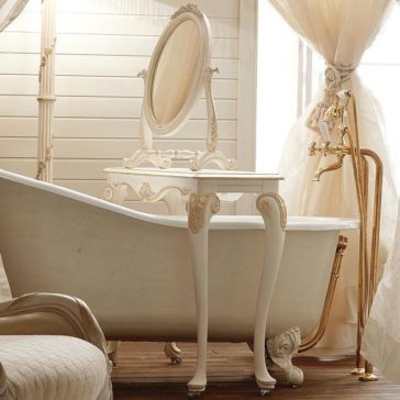 Designer Italian Rococo Console Table with mirror A luxurious, vintage-style bathroom showcases a clawfoot bathtub adorned with ornate designs. The room is elegantly complemented by a Designer Italian Rococo Console Table with mirror, perfectly matching the sophisticated vanity. Cream-colored curtains and light wood paneling further enhance the classic and refined ambiance of the space.