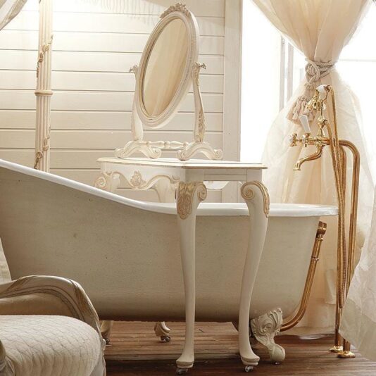 A luxurious, vintage-style bathroom showcases a clawfoot bathtub adorned with ornate designs. The room is elegantly complemented by a Designer Italian Rococo Console Table with mirror, perfectly matching the sophisticated vanity. Cream-colored curtains and light wood paneling further enhance the classic and refined ambiance of the space.