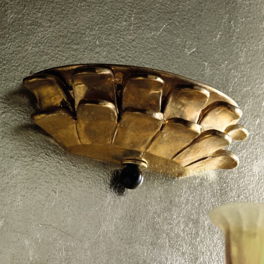 The Luxury Gold Plated Classic Italian Wall Light is a luxurious, flower-shaped wall sconce featuring petal designs, mounted on a textured metallic wall. This elegant fixture boasts a black bead at its base and partially reveals its glass shade at the bottom right.