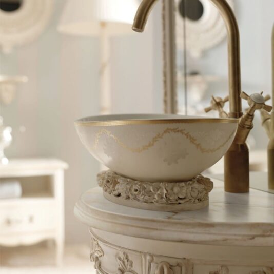 Opulent Italian Bathroom Console with Mirror Elegant bathroom with the Opulent Italian Bathroom Console with Mirror, featuring a luxurious sink with a marble basin adorned with golden accents and delicate patterns, set on a carved floral pedestal. The brass faucet complements the antique-style decor, and the mirror reflects soft lighting to enhance the serene atmosphere.