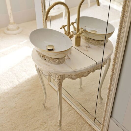 Opulent Italian Bathroom Console with Mirror The Opulent Italian Bathroom Console with Mirror showcases an elegant oval porcelain sink adorned with ornate gold fixtures, beautifully set against a mirrored wall. The vanity boasts intricate carvings and delicate legs, gracefully resting on a plush, cream-colored carpet. This luxurious piece embodies an elegant and vintage-inspired aesthetic.