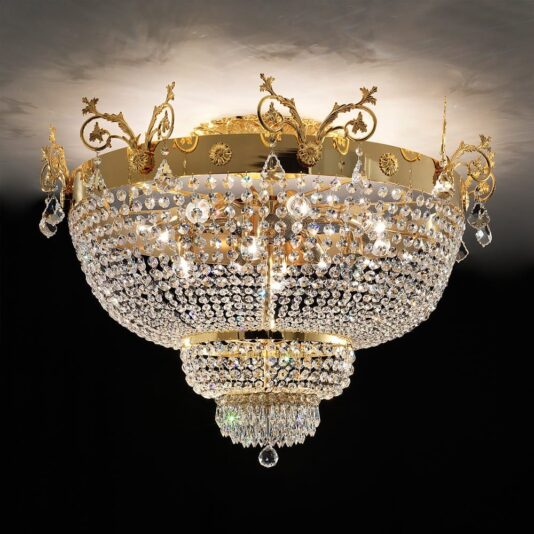 Experience luxury with our Ornate Gold and Crystal Empire Ceiling Light, featuring intricate gold detailing and multiple tiers of hanging crystals. This chandelier boasts a round shape adorned with ornate patterns and is warmly illuminated from within, casting an elegant glow against a dark backdrop.