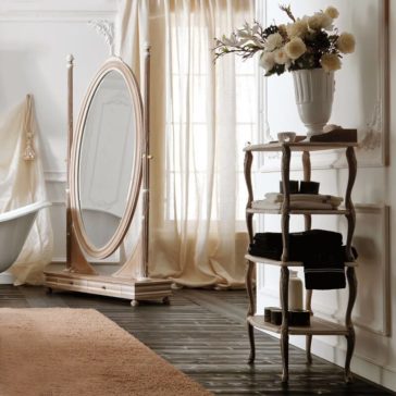 Wooden Italian Freestanding Bathroom Shelves A sophisticated bathroom features an ornate oval standing mirror, a white bathtub, elegant sheer curtains, and Wooden Italian Freestanding Bathroom Shelves holding black and white towels. A tall vase with white flowers tops the shelves, enhancing the ambient, classic decor.
