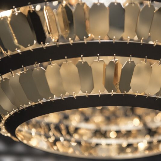 Italian Contemporary Designer Pendant A close-up shot of an Italian Contemporary Designer Pendant with an intricate design. The pendant features multiple tiered rows of rectangular glass or metallic pieces, emitting a warm, golden light that creates a sparkling effect and adds an elegant touch to the decor.