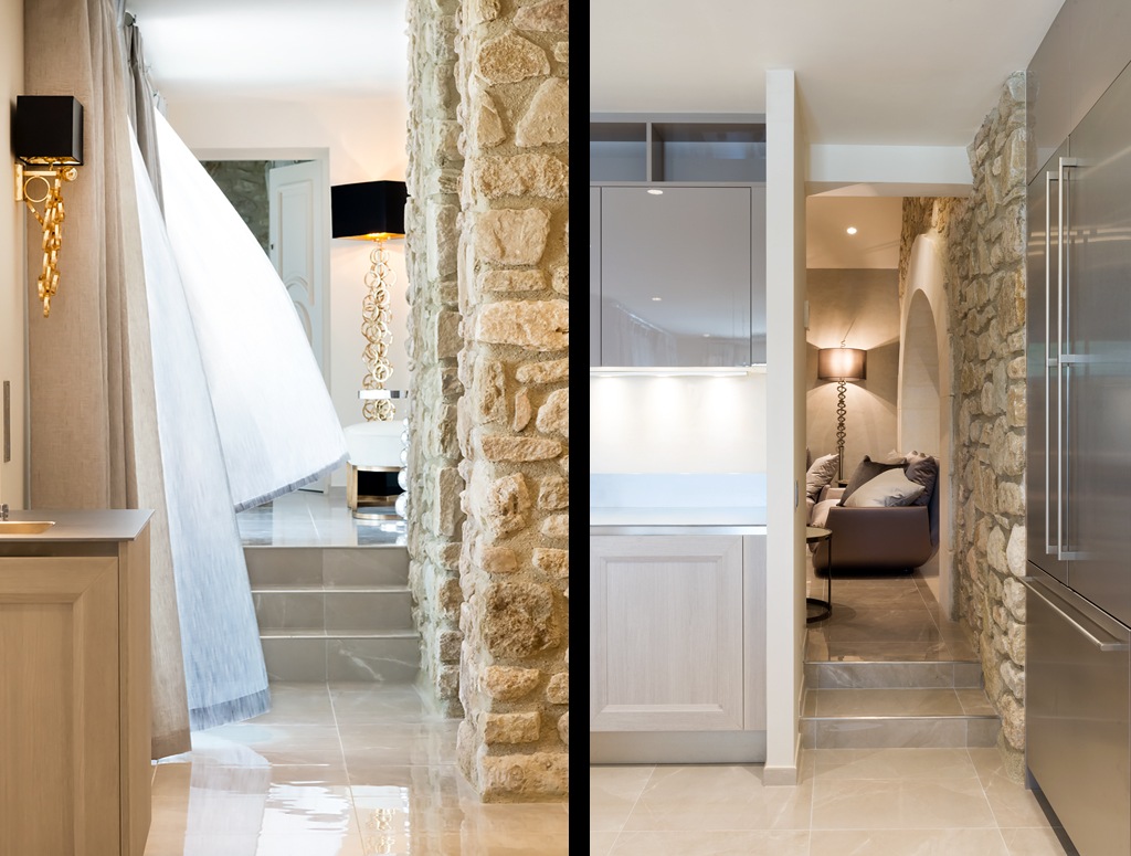 A split image. On the left, a modern kitchen with stone walls opens to a bright room behind a flowing white curtain. On the right, a cozy area with a couch, lamp, and stone archway is visible through a doorway under a stepped entrance with stone walls.