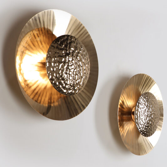 Two Designer Gold Plated Hammered Round Wall Lights with a golden hue. Each fixture features a circular base and a textured, hammered centerpiece, reflecting and scattering the light to create an elegant and warm illumination on the wall.