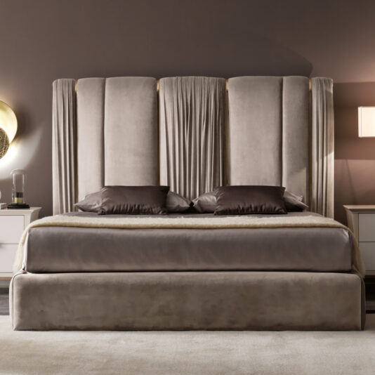 A modern bedroom with the Italian Pleat Upholstered Velvet Bed, tall plush headboard, gray and dark accent pillows, matching bedding, plus a nightstand and wall-mounted light on each side.