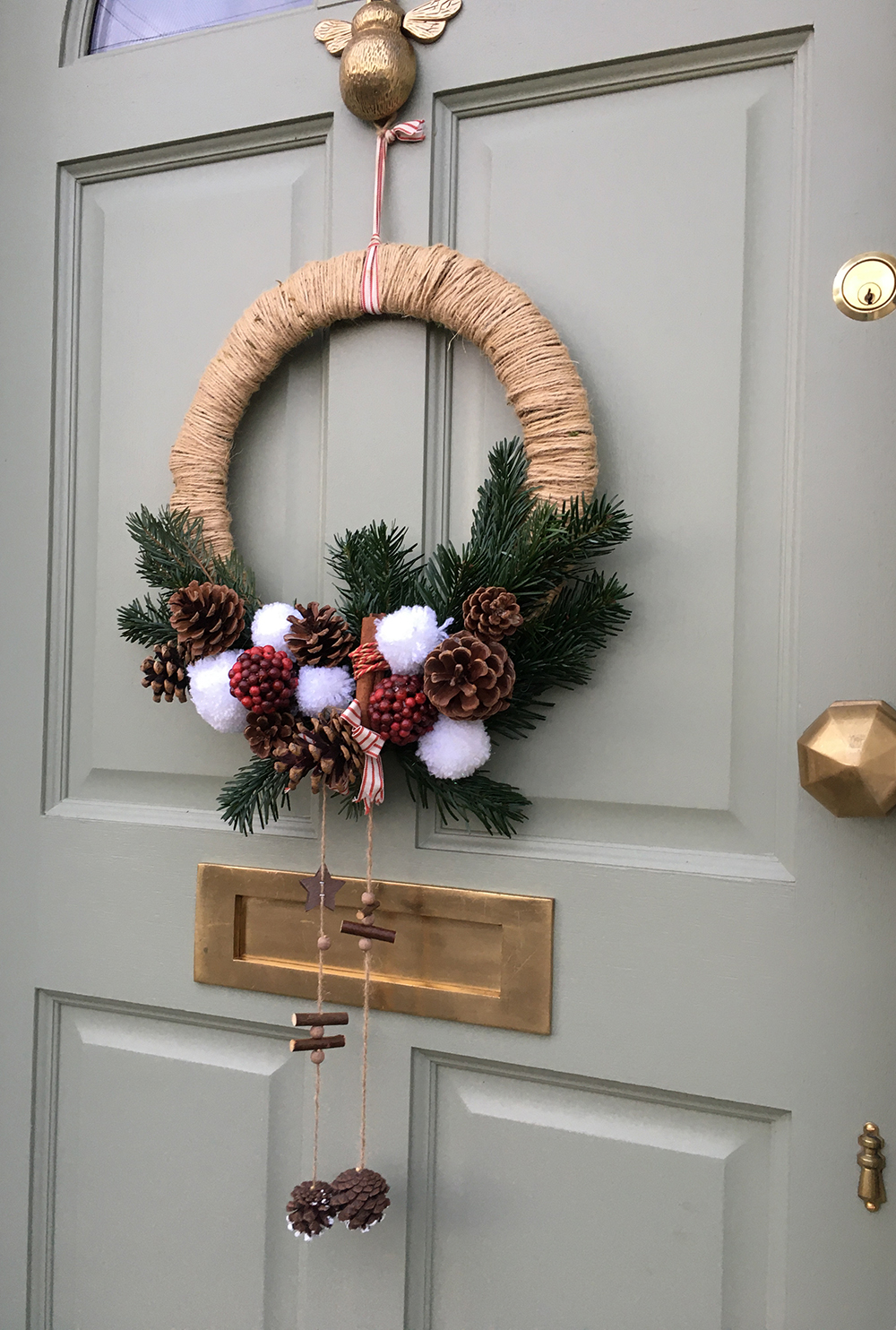 Contemporary Christmas wreath, rope bound hoop with natural evergreen foliage, cones, berries, snowball pom poms