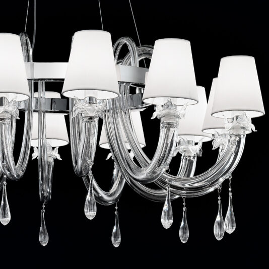 Clear Murano Glass Chandelier With Silk Shades Introducing the Clear Murano Glass Chandelier With Silk Shades—a luxurious chandelier featuring teardrop-shaped crystal pendants. Its curved glass arms elegantly support each silk shade, crafting a sophisticated design that stands out against a black background.