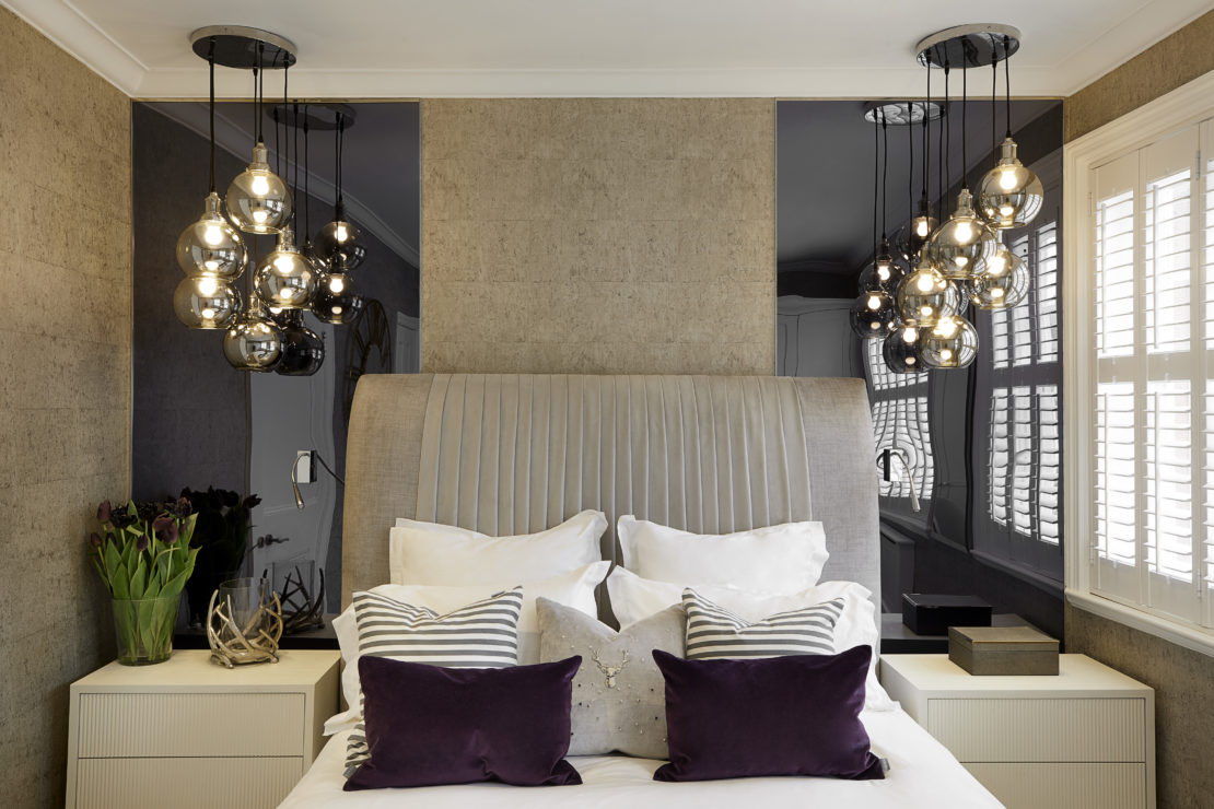 Luxury bedroom with a large bed and impressive headboard at the centre.