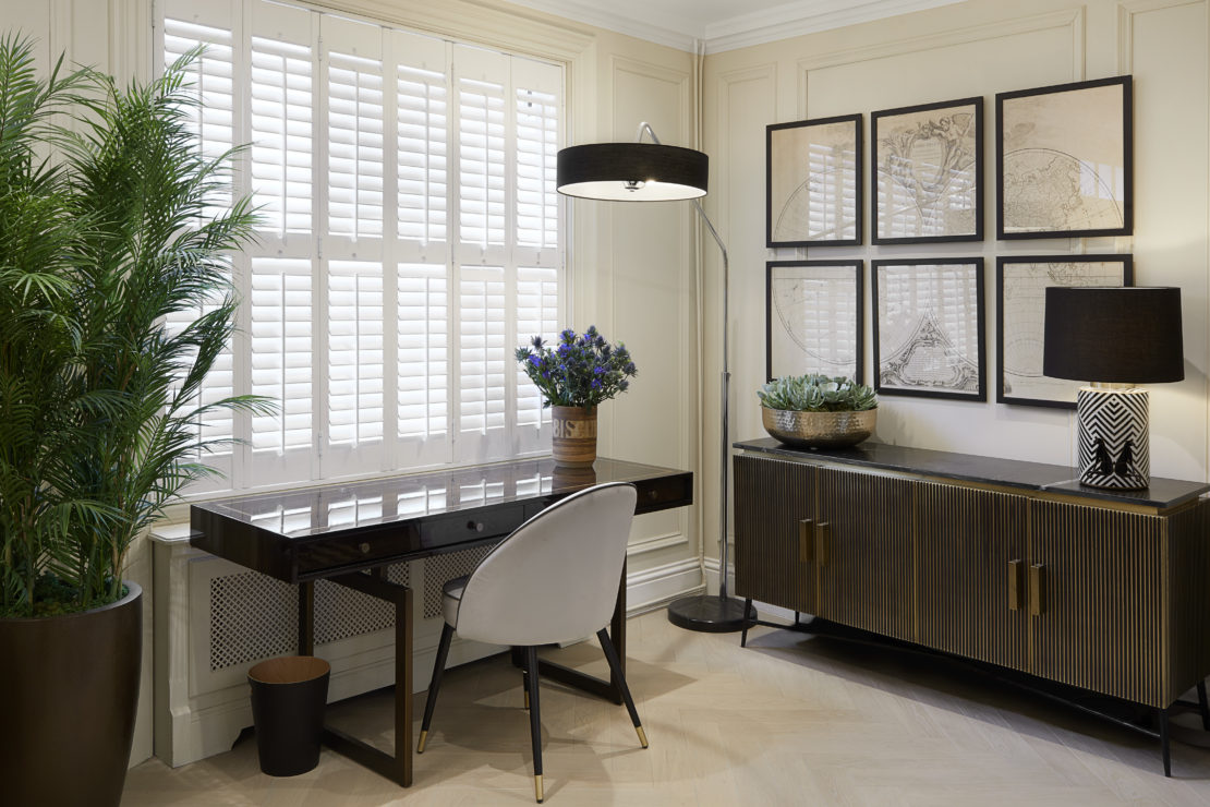 Luxury home with writing desk and chair and side board with black and white lamp, with 6 pieces of artwork on the walls