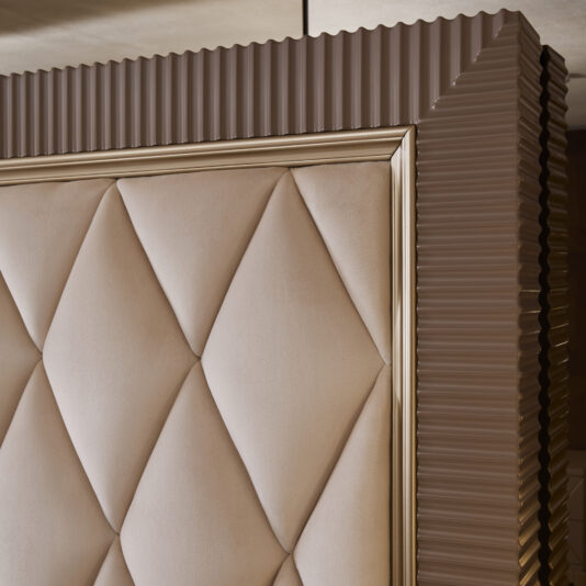 Art Deco Inspired Upholstered Storage Bed with Tall Headboard Close-up of an upholstered panel from the Art Deco Inspired Upholstered Storage Bed with Tall Headboard, showcasing a diamond-patterned beige fabric and a ribbed brown frame accented with a metallic gold border. The detailed texture and design reflect high-quality craftsmanship, reminiscent of elegant Italian designer pieces.