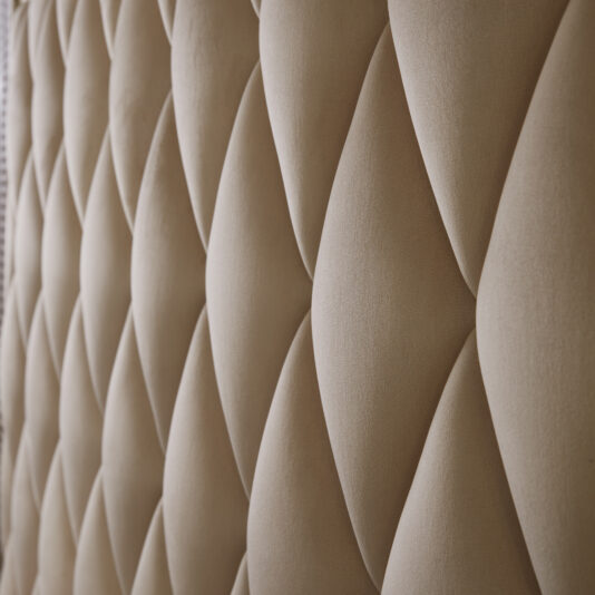 Art Deco Inspired Upholstered Storage Bed with Tall Headboard Close-up view of a beige, tufted fabric surface with a diamond pattern on the Art Deco Inspired Upholstered Storage Bed with Tall Headboard. The texture appears plush and soft, giving a luxurious feel. The lighting highlights the depth of the tufts and creates subtle shadows in the folds, showcasing Italian designer elegance.