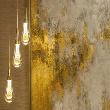 Set of 3 Glass Drop Pendant Lights A Set of 3 Glass Drop Pendant Lights with golden accents hang on the left side against a textured wall adorned with abstract gold and silver paint splashes, creating a modern and artistic ambiance.