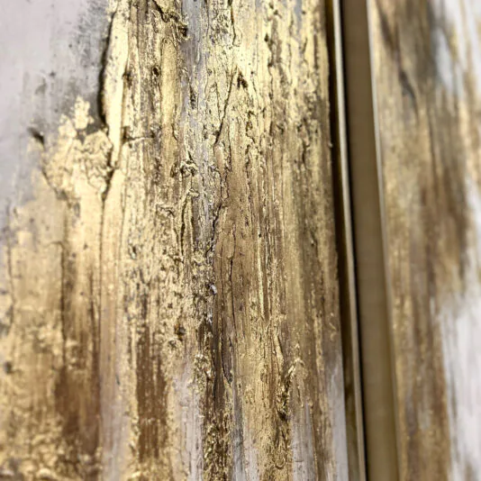 Original Gold Leaf Abstract Painting Close-up of the Original Gold Leaf Abstract Painting featuring a textured wall with gold and beige tones. The surface appears rough and uneven, with streaks and patches of gold paint, creating a luxurious, abstract look. The image captures the intricate details and depth of the texture.