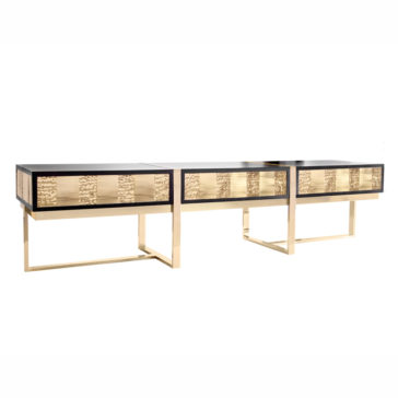 Introducing the Art Deco Inspired TV Unit: a modern console table showcasing a sophisticated black tabletop and eye-catching gold textured accents along the drawer fronts. It is elegantly supported by sleek, rectangular gold legs, offering a stylish and contemporary aesthetic.