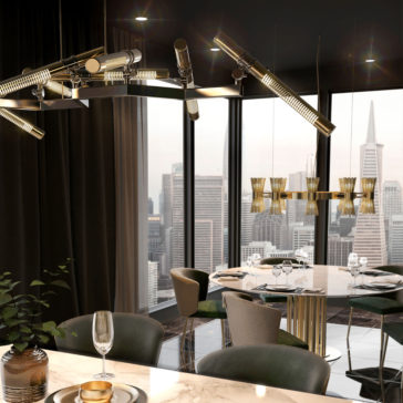 A modern dining room with a view of the city skyline features the Contemporary Statement Chandelier, a marble dining table set with elegant green upholstered chairs, and large floor-to-ceiling windows. A glass of wine and a gold plate rest on the table in the foreground.