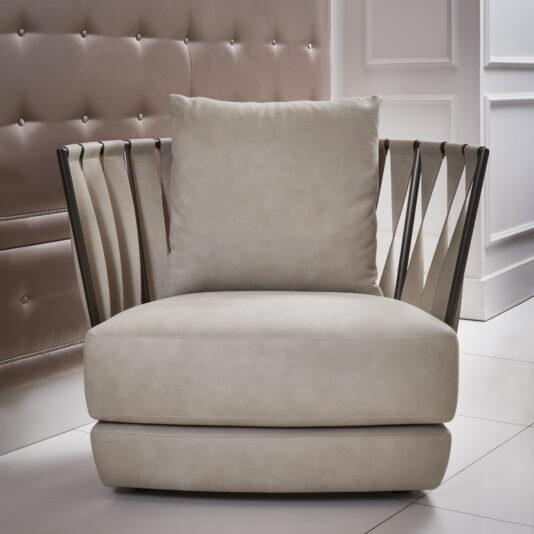 The Luxury Modern Leather Twist Armchair, featuring a light gray leather finish, a plush square cushion, and unique artistic black metal armrests that resemble ribbons, is set on a white tiled floor against a backdrop of a button-tufted beige wall and a white paneled wall.
