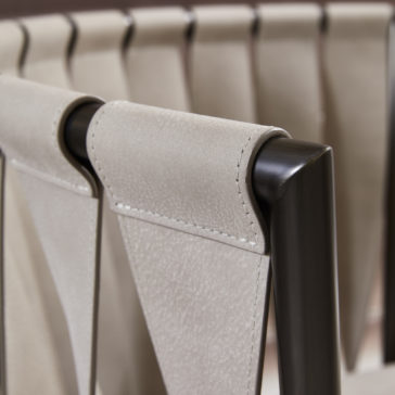Luxury Modern Leather Twist Armchair Close-up of the backrest of the Luxury Modern Leather Twist Armchair, featuring exquisite beige suede-like upholstery and a sleek dark wooden frame. The backrest showcases a distinctive folded-over design with visible stitching details, highlighting its contemporary and elegant craftsmanship.