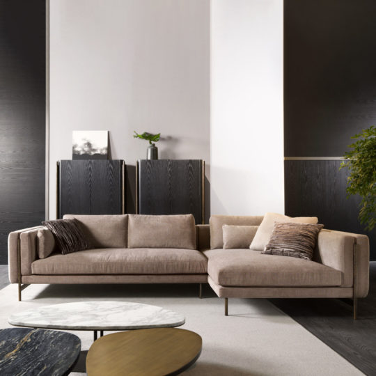 A modern living room features the Contemporary Corner Sofa, neutral cushions, a two-tier coffee table with marble and wood surfaces, dark wood cupboards, a potted plant, and minimalist decor set against black and white walls.