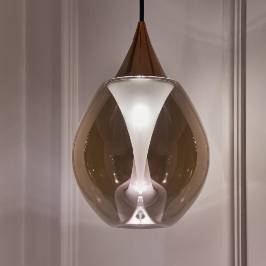 Exclusive Glass Pendant Light Cluster The Exclusive Glass Pendant Light Set includes a chic, teardrop-shaped glass shade with a stunning metallic finish, all suspended from a delicate black cord. Inside, the light bulb emits a gentle glow that accentuates the sophisticated design against a white backdrop.