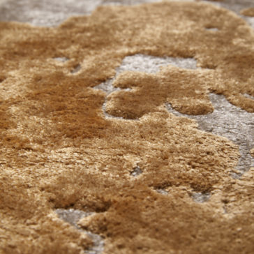 High Quality Abstract Hand Woven Rug Close-up of a High Quality Abstract Hand Woven Rug featuring luxurious, high-quality craftsmanship. The rug showcases a mix of beige, brown, and gray tones with a plush, slightly irregular pattern that gives it a rich and cozy appearance, reminiscent of natural landscapes or abstract art.