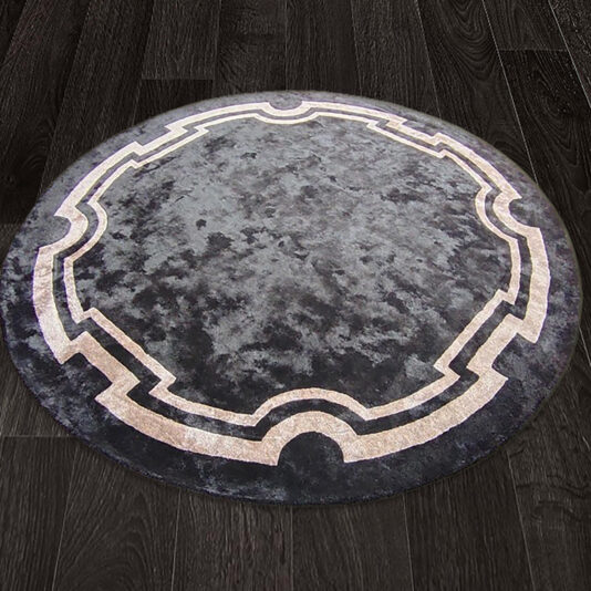 A High Quality Hand Woven Round Rug with a dark grey textured surface is placed on a dark wooden floor. This two-tone rug features a lighter grey border with a geometric pattern, adding contrast to its design.