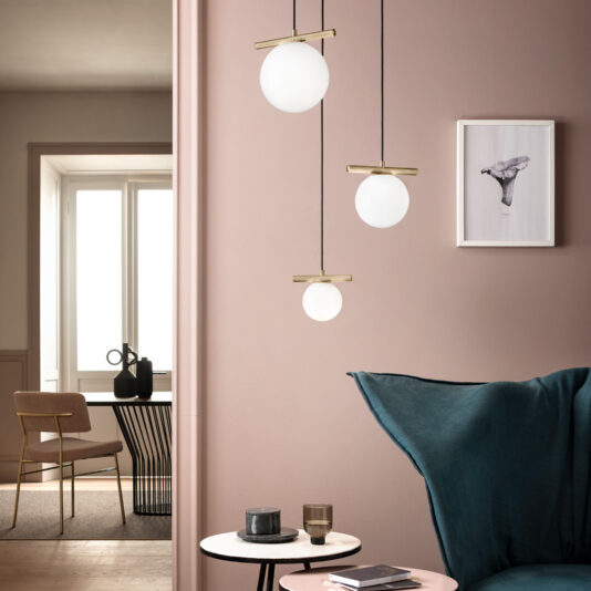 Modern Murano Glass Pendant Light Cluster A modern, softly lit living space with a teal sofa, a round pink side table adorned with decor, and a stunning **Modern Murano Glass Pendant Light Cluster** illuminating the room. The walls are painted in muted pink hues and feature a small framed art piece. In the background, you can see a dining area complete with a table and chairs.