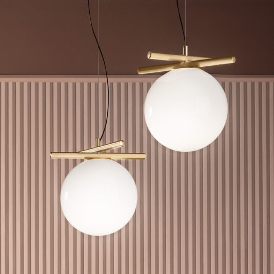 Modern Murano Glass Pendant Light Two modern pendant lights with spherical white shades hang from the ceiling. Each light is suspended by black cords and features a brass horizontal bar above the globe. The lights are set against a brown and pink striped wall background.