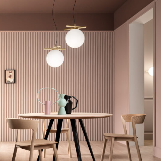 Modern Murano Glass Pendant Light A modern dining room features a round wooden table with two chairs. Above the table are two spherical pendant lights. The room has textured pink walls, decorative vases on the table, and a small framed picture on the wall.