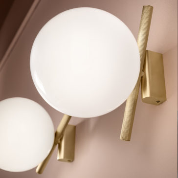 Modern Murano Glass Wall Light Close-up of the Modern Murano Glass Wall Lights featuring large, round white globes and gold cylindrical bases, set against a soft pink wall.