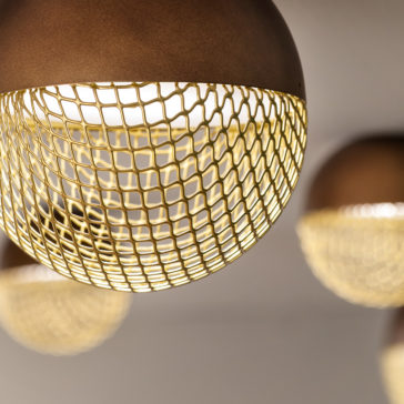 Modern Round Ceiling Light Close-up of the Modern Round Ceiling Light featuring a spherical metal grid cage surrounding the bulb. The grid creates a warm, geometric pattern as it diffuses the light. The background is softly blurred, showcasing similar ceiling lights from the collection in the distance.