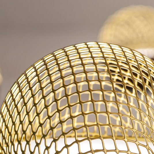 Modern Round Pendant Chandelier Close-up of the Modern Round Pendant Chandelier featuring a spherical, lattice-style, gold-colored light fixture. The grid pattern creates a geometric decorative effect as it partially covers the bulb inside, giving a stylish appearance. Another similar light fixture is blurred in the background.