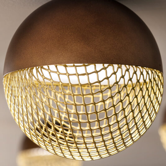 Modern Round Pendant Light A close-up view of the Modern Round Pendant Light fixture reveals its contemporary half-sphere design. The top half features a smooth, matte brown finish, while the bottom half is crafted from gold-colored mesh that filters warm light through. This textural contrast enhances its industrial-chic aesthetic.