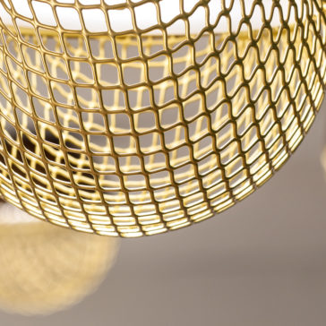 Close-up of the Modern Round Pendant Light, featuring a golden metal mesh lamp with a grid pattern. The lamp is illuminated, casting warm light and shadows through the intricate grid design of the lampshade, while the background remains blurred to highlight its details.