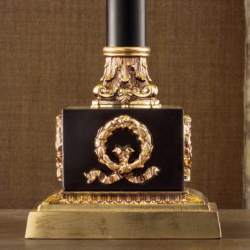 Classic Louis Table Lamp The image showcases the Classic Louis Table Lamp base, featuring an intricate design with ornate gold detailing. The base includes a black block embellished with a gold laurel wreath and ribbon motif. The overall aesthetic is opulent and classical, boasting a rich, sophisticated finish.