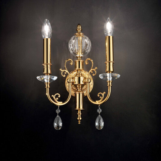 The Classic Transparent Gold Wall Light features an ornate design with two candle-shaped light bulbs, intricate scrollwork, and decorative crystal accents against a dark background. This elegant fixture includes a central glass orb and hanging crystal pendants, enhancing its luxurious appearance.