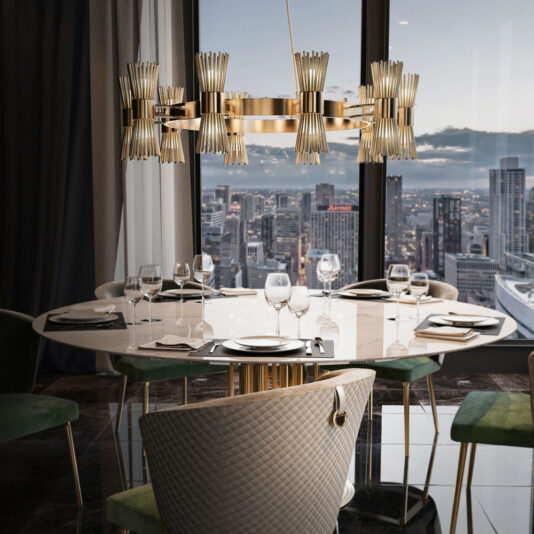 Contemporary Gold Plated Chandelier A luxurious dining room features a round marble table set with elegant tableware and surrounded by modern, green velvet chairs. The striking Contemporary Gold Plated Chandelier hangs above the table, casting a warm glow. Floor-to-ceiling windows reveal an urban cityscape view at dusk.