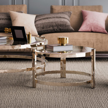 Contemporary Luxury Glass Coffee Tables A modern living room featuring a beige couch adorned with striped and pink pillows, a beige carpet, and luxurious Contemporary Luxury Glass Coffee Tables. The tables hold books, a golden decorative item, and a framed photo. The room boasts a neutral color palette with metallic accents.